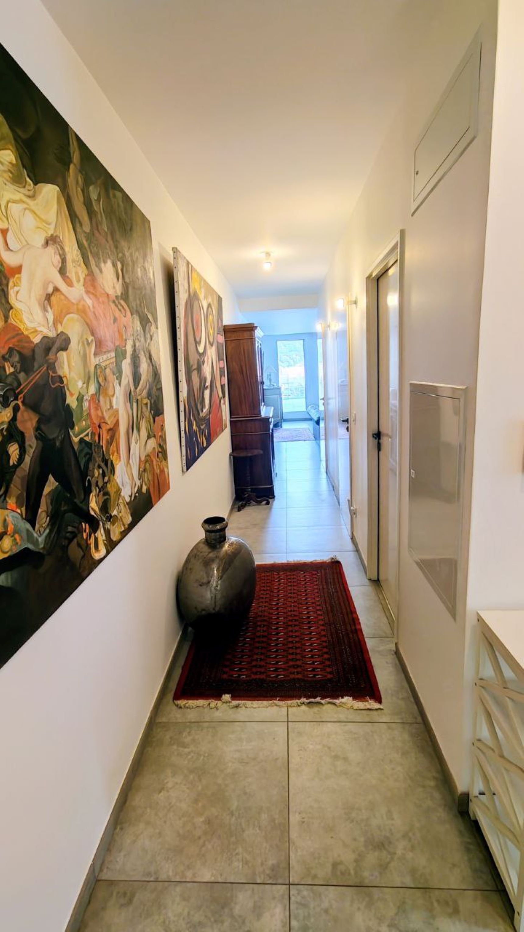 A hallway with a large abstract painting, a rug, and a door.