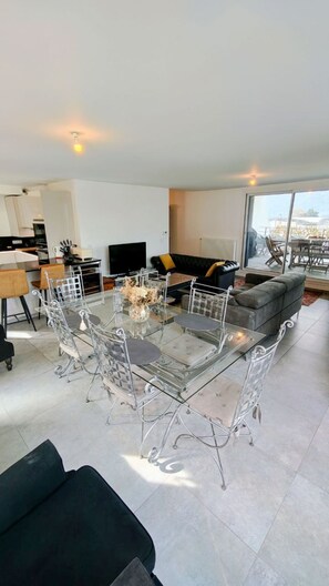 A modern living room with a glass dining table, a sofa, and a large window offering a view. - T3 Dolce Bateau, a 5-minute walk from the 3*-rated lake (Aix-les-Bains)
