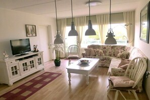 Ein Wohnzimmer mit Fernseher, weißem Schrank, floralem Sofa und Couchtisch.