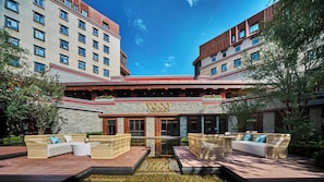 A hotel with a stone facade, outdoor seating area, and a clear sky.