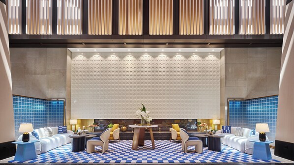 A modern lobby with a checkered floor, a central round table, and seating arrangements.