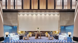A modern lobby with a checkered floor, a central round table, and seating arrangements.