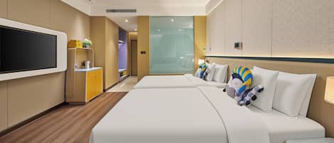 Habitación de hotel con un televisor de pantalla plana grande, un minibar, una cama con almohadas decorativas y vista al pasillo.