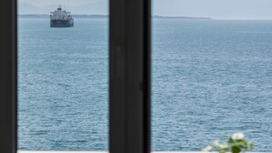 A view of the sea from a balcony with a ship in the distance. - True Blue by halu! - Seafront 2BR apartment (Thessaloniki)