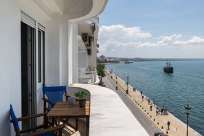 Un balcone con vista sul mare, un tavolo con sedie e una pianta in vaso.