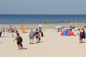 Ein Strand mit Menschen, Zelten und Sonnenschirmen.
