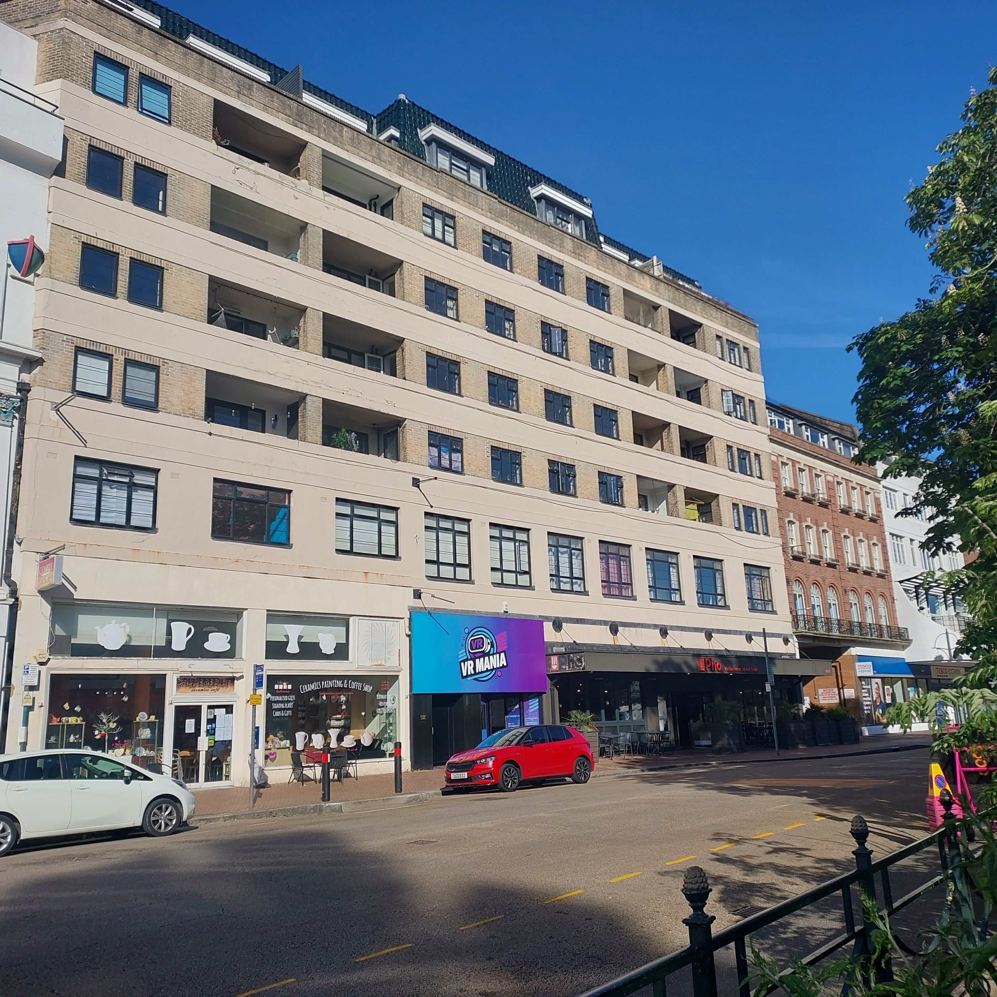 A multi-story hotel with a ground-level coffee shop and a VR Mania sign.