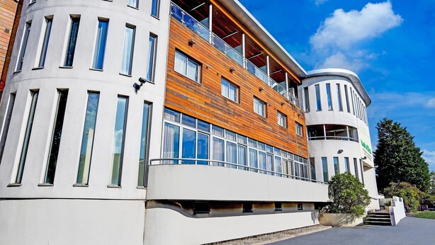Een modern gebouw met een gebogen gevel, grote ramen en een houten paneel accent.