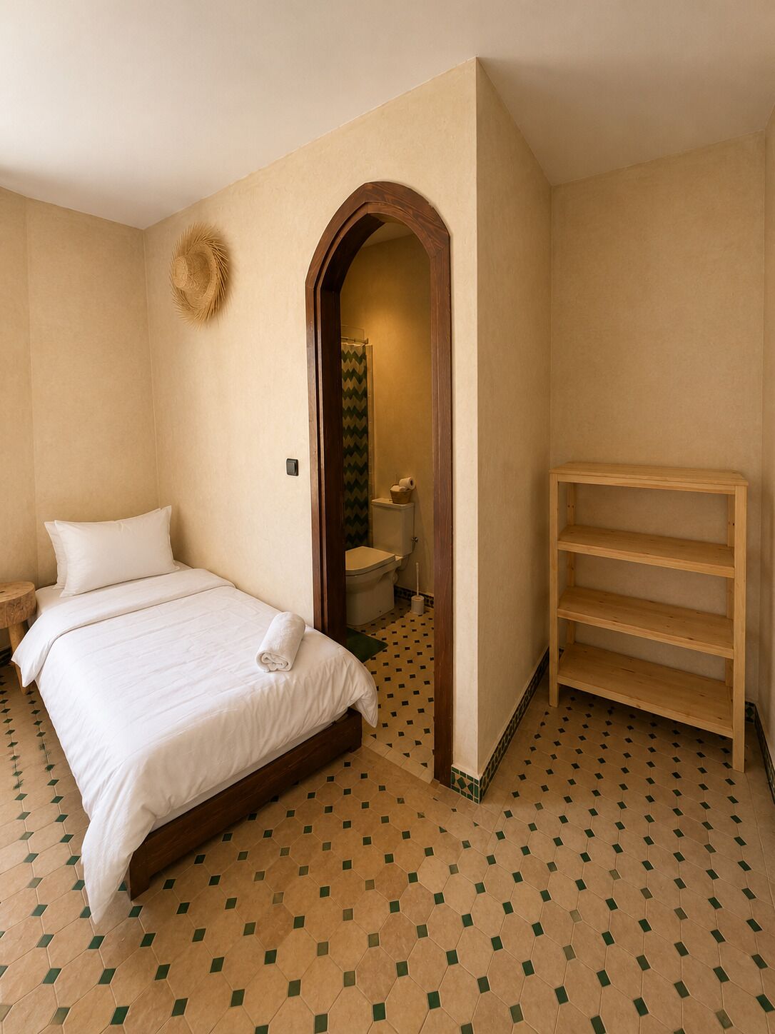 A bedroom with a bed, a wooden shelf, a bathroom with a shower, and a tiled floor.