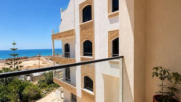 A balcony with a view of a beach and a building with decorative window frames.
