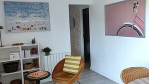 Ett modernt vardagsrum med en soffa, en fåtölj, ett bord, en bokhylla och en tavla som föreställer en cykel.