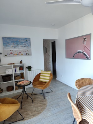 Ein modernes Wohnzimmer mit einer Couch, einem Sessel, einem Tisch, einem Bücherregal und einem Gemälde eines Fahrrads.