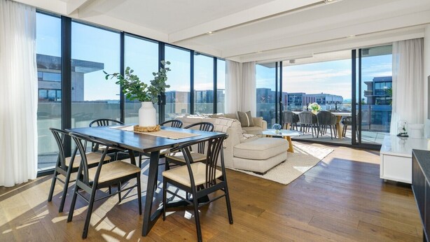 A modern living room with a dining area, large windows, and a view of the cityscape. - Sub-Penthouse with Lake Views | Kingston Foreshore (Kingston)