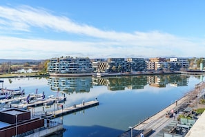A marina with boats docked, a waterfront promenade, and modern buildings with balconies. - Sub-Penthouse with Lake Views | Kingston Foreshore (Kingston)