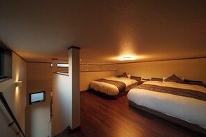 Hotellihuone, jossa on kaksi sänkyä, televisio ja puulattia.