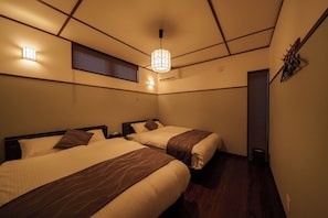 Quarto de hotel com duas camas, luminária no teto, ar-condicionado fixado na parede e janela com persianas.