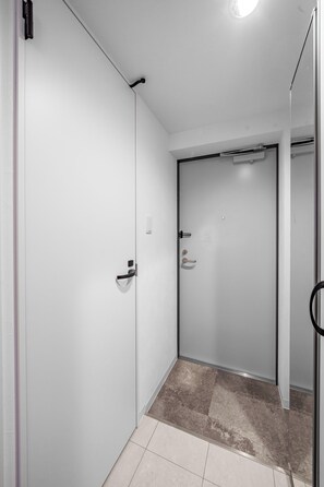 A hallway with a white door, a small window, and a tiled floor. - ASTAGE CHITOSE SUEHIRO 105 (Chitose)