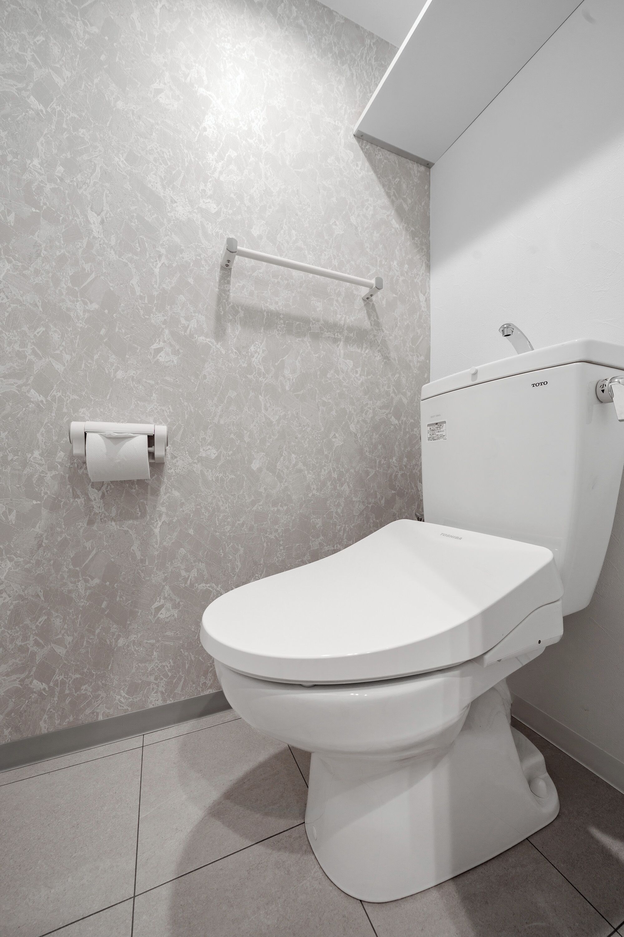 Un bagno moderno con un water, un portasciugamani di carta e un portasciugamani a parete.