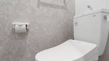 Un bagno moderno con un water, un portasciugamani di carta e un portasciugamani a parete.