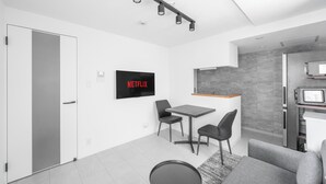 Una sala moderna con un televisor de pantalla plana, una mesa de comedor y una zona de cocina.