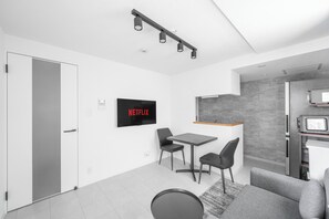 Una sala moderna con un televisor de pantalla plana, una mesa de comedor y una zona de cocina.