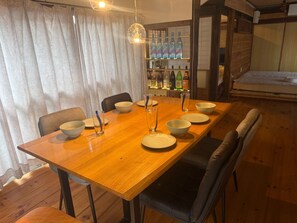 Un comedor con mesa de madera, sillas y una zona de bar con botellas.