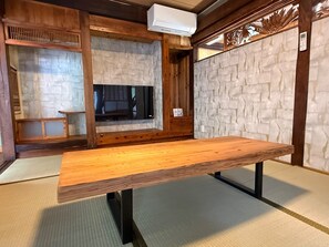 Ein Holztisch mit einer Bank, eine Steinmauer und ein Fenster mit Blick.