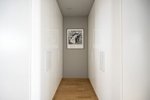 A hallway with white walls and a wooden floor, leading to a framed black and white photograph on the wall. - Skyflats Vienna Black View (Wien)