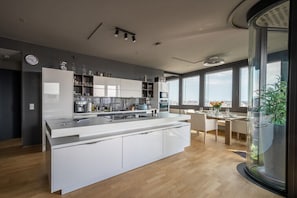 A modern kitchen with a central island, built-in appliances, and a dining area with a view. - Skyflats Vienna Black View (Wien)