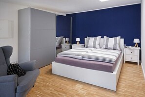 Ein modernes Schlafzimmer mit einem großen Bett, Nachttischen und einem grauen Sofa.