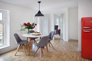 Eine moderne Küche mit Essbereich, einem roten Kühlschrank und einer Vase mit Blumen auf dem Tisch.