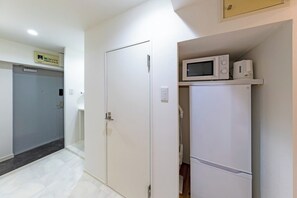 A hotel room with a closed door, a microwave on a shelf, and a small refrigerator. - Opening in 2026 1 minute walk from Tojinmachi St / Fukuoka City Fukuoka (Fukuoka City)