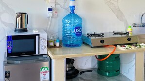 Eine kleine Küchenzeile mit Mikrowelle, Kühlschrank, Gasherd und Wasserspender.