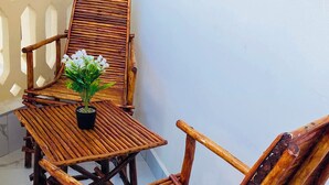 Ein Balkon mit Holztisch und -stühlen, einem Blumentopf und einem Fenster.