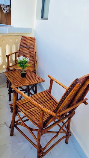 A balcony with a wooden table and chairs, a potted plant, and a window. - Beach studio - 2 minutes walk to beach in peaceful Diani Beach with AC (Diani Beach)
