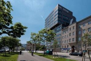 A modern building with multiple floors, a paved walkway, and trees. - Skyflats Vienna Hills View (Wien)