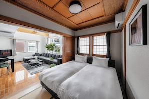 Ein Hotelzimmer mit Bett, Sofa, Fernseher und Blick ins Freie.
