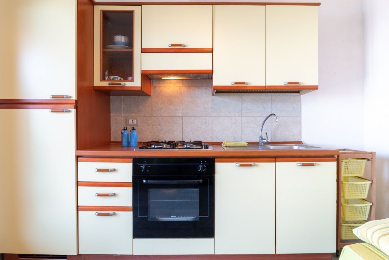 A kitchen with a stove, oven, sink, and cabinets.