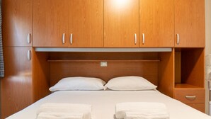 Ein Hotelzimmer mit Holzschrank, einem Bett mit weißer Bettwäsche und zwei Handtüchern auf dem Bett.