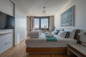Ein modernes Hotelzimmer mit einem großen Bett, einem Fernseher, Blick auf die Stadt und einem Gemälde an der Wand.