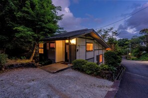 Ein kleines, modernes Haus mit Satteldach, einer Veranda und einem Schotterweg.