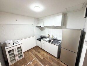 Una cucina compatta con mobili bianchi, forno a incasso, lavello e frigorifero.
