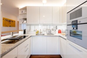 Eine moderne Küche mit weißen Schränken, einer Granit Arbeitsplatte und integrierten Geräten, darunter ein Herd und ein Backofen.