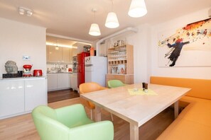 Eine moderne Küche mit weißen Schränken, einem roten Kühlschrank und einem Essbereich mit Tisch und Stühlen.