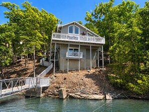 Ein zweistöckiges Haus mit Balkon, einem roten Stern auf dem Dach und einem Steg, der ins Wasser führt.