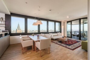 A modern living room with a dining area, large windows, and a view of a cityscape. - Skyflats Vienna City View (Wien)