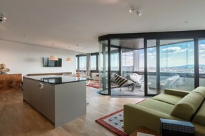 A modern living space with a kitchen, a dining area, and a balcony with a city view. - Skyflats Vienna South View (Wien)