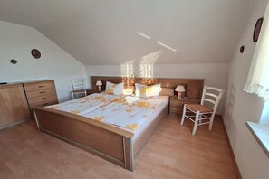 A bedroom with a bed, bedside tables, a chair, and a dresser. - Holiday apartment in Rieth with swimming pool (Rieth)