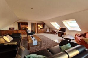 An attic living space with a sofa, coffee table, TV, and skylights. - Holiday apartment in Rieth with swimming pool (Rieth)