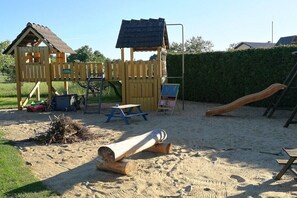 A playground with a wooden playhouse, a slide, and a picnic table. - Holiday apartment with 2 bedrooms (Lübben\/Spreewald)